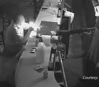 Man in St. Louis bar lights cigarette while ignoring armed robber